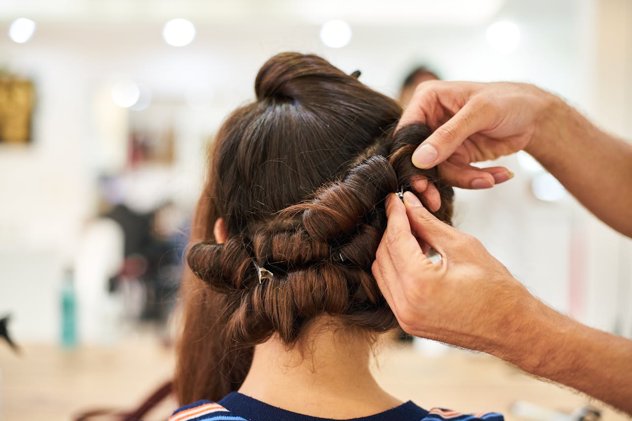 about-03 Close-up of a stylist crafting an intricate updo hairstyle in a modern salon.
