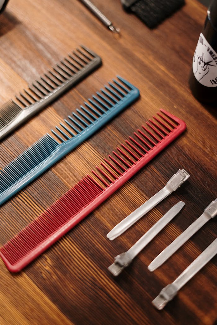 Close-up of various hair salon tools, including colorful combs, on a wooden surface.