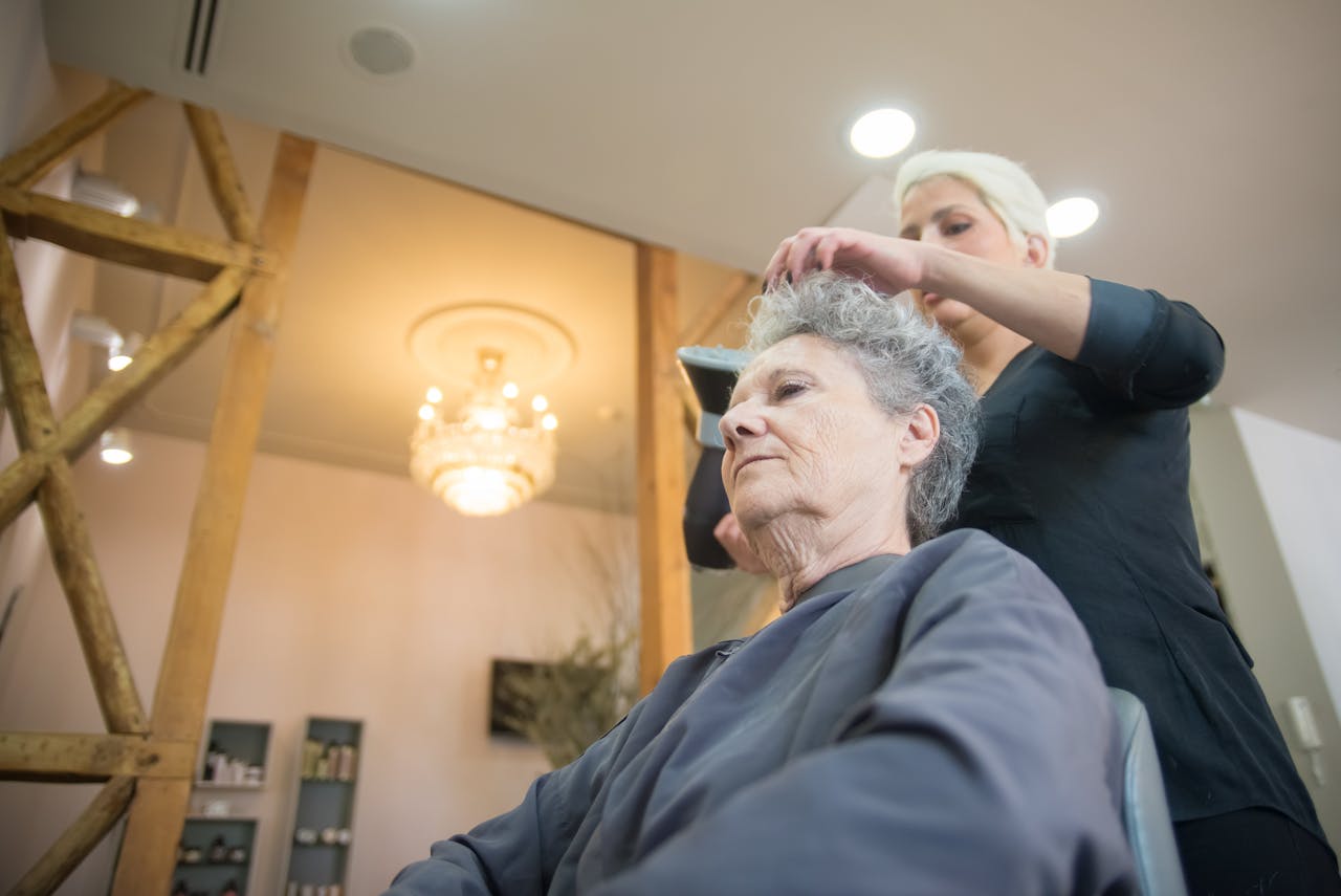 A senior woman having her hair styled by a professional hair stylist in a modern salon.