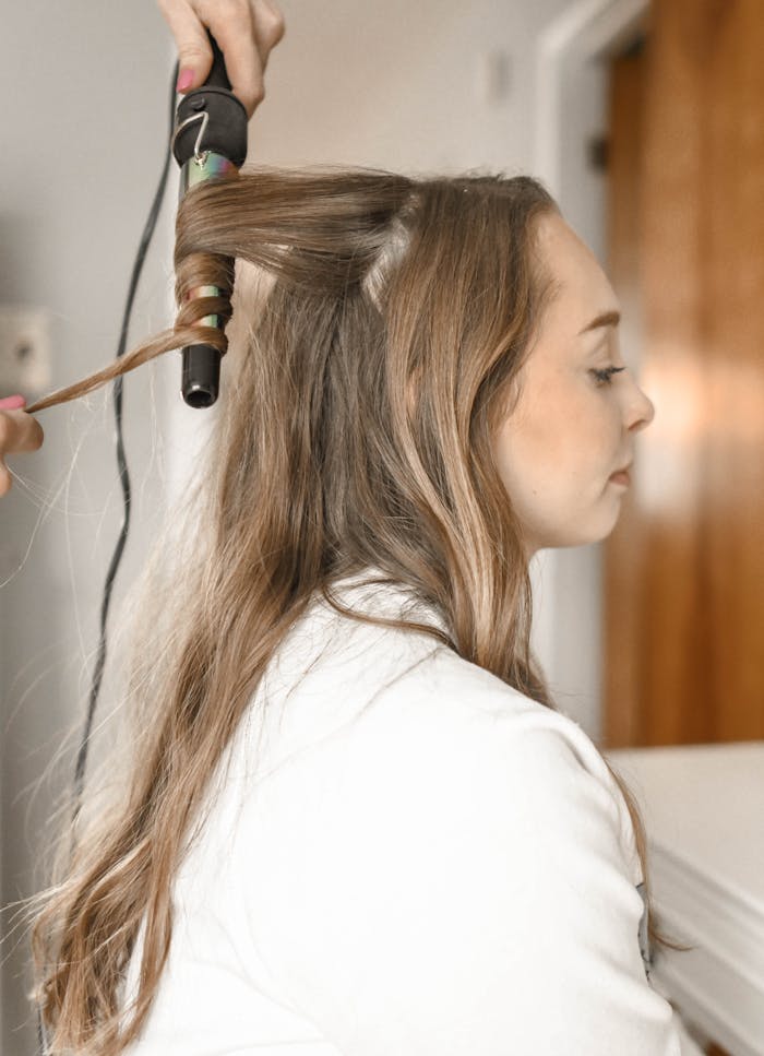 about-04 Profile of a woman having her hair curled with an iron in a salon setting.